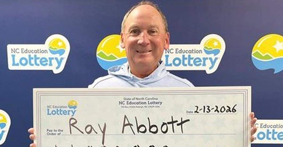 Ray Abbott smiles while holding a large ceremonial check from the NC Education Lottery for $1,000,000. The check is dated February 13, 2026, and is marked as a ‘Second Chance’ win. He is standing in front of a blue backdrop patterned with the NC Education Lottery logo.