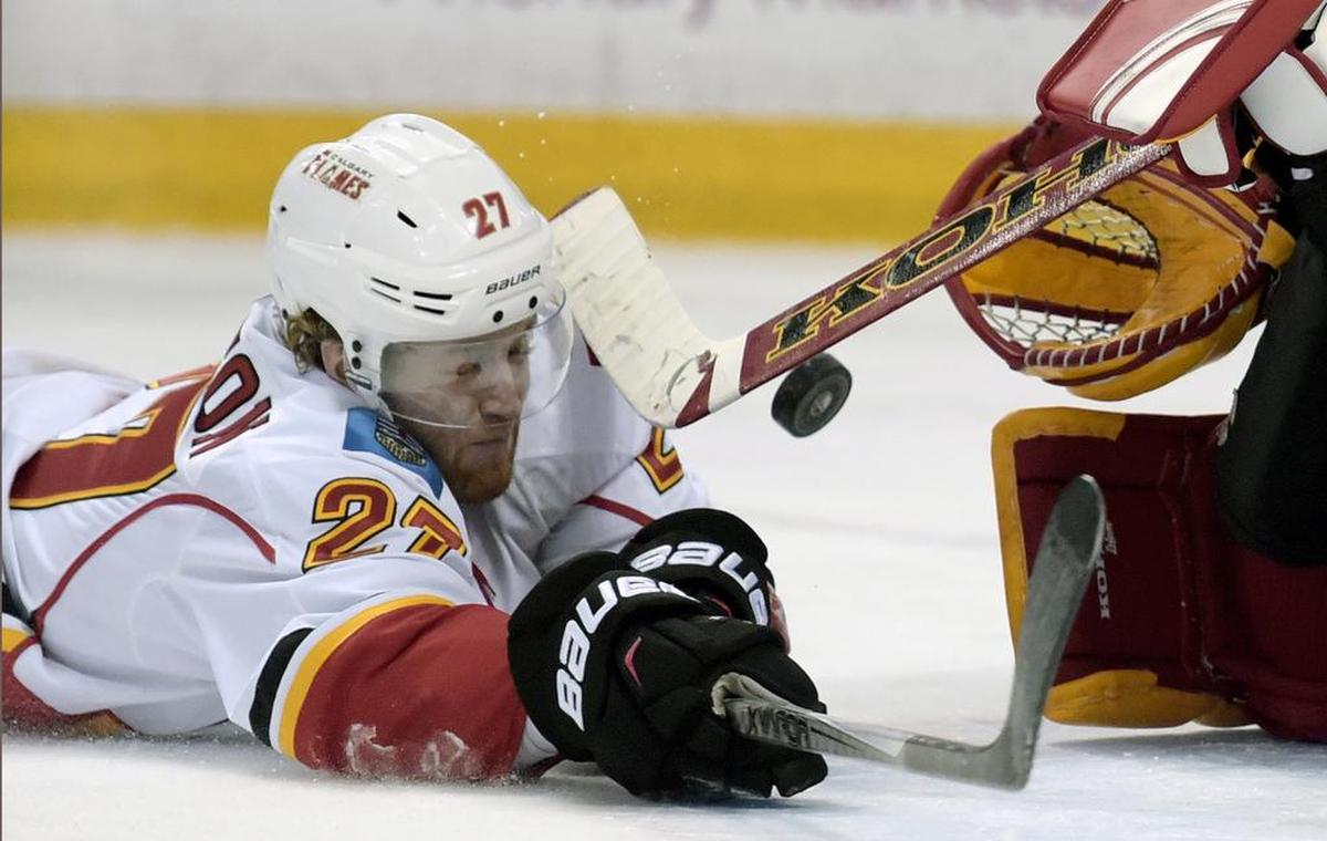Calgary Flames defenseman Dougie Hamilton (27) slides across the goal crease to knock away the puck as goaltender Jonas Hiller, right, defends during the third period of an NHL hockey game against the Buffalo Sabres, Thursday, March 3, 2016, in Buffalo, N.Y. Buffalo won 6-3. (AP Photo/Gary Wiepert)