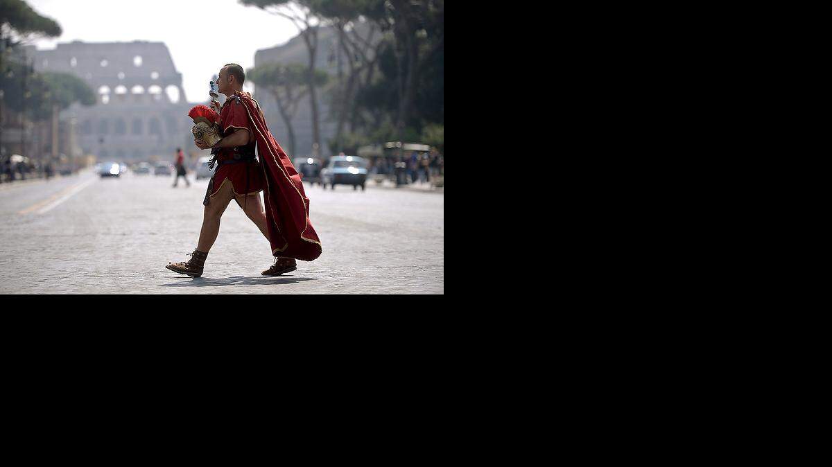
A man dressed as a ancient Roman centurion walks by the Colosseum in the center of Rome on April 15, 2015.
