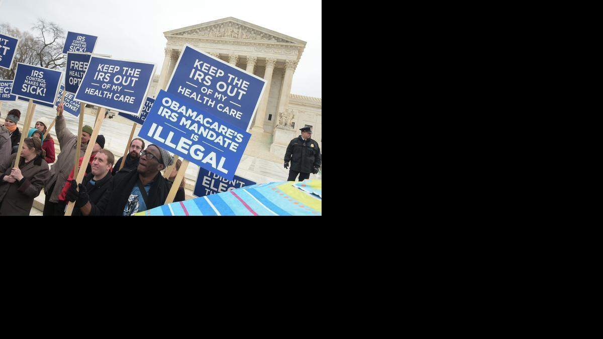 
Protesters hold placards Wednesday challenging the Patient Protection and Affordable Care Act outside the US Supreme Court. 
