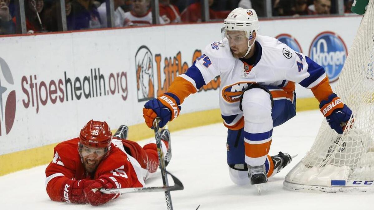Detroit Red Wings center Riley Sheahan and New York Islanders defenseman Calvin de Haan (44) reach for the puck in the second period of an NHL hockey game Saturday, Feb. 6, 2016, in Detroit.