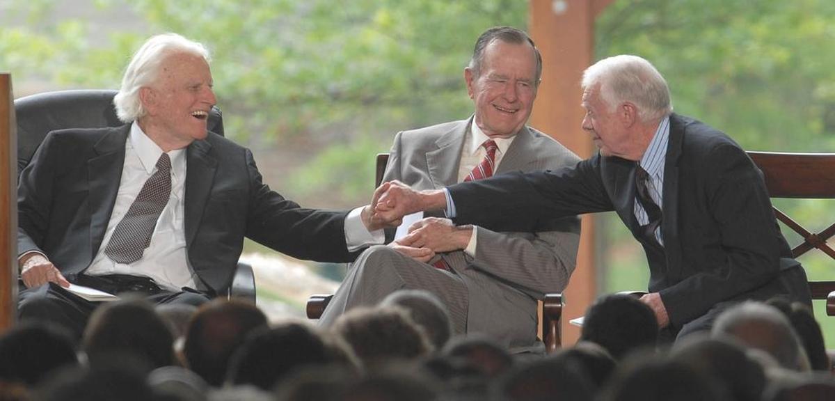 Billy Graham shakes hands with Jimmy Carter as George H.W. Bush looks on at the dedication of The Billy Graham Library in 2007