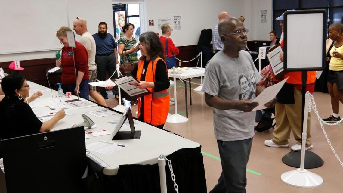 A Wake county voter, right, moves toward the voting booth after obtaining his ballot at the Herbert C. Young Community Center early voting site in Cary March 11, 2016.