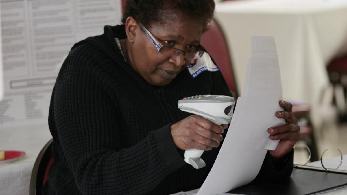 Chapel Hill Northside precinct poll worker Susan Headen scans the bar codes on a ballot so it will match up with a voter ID during a primary election on May 6, 2014.