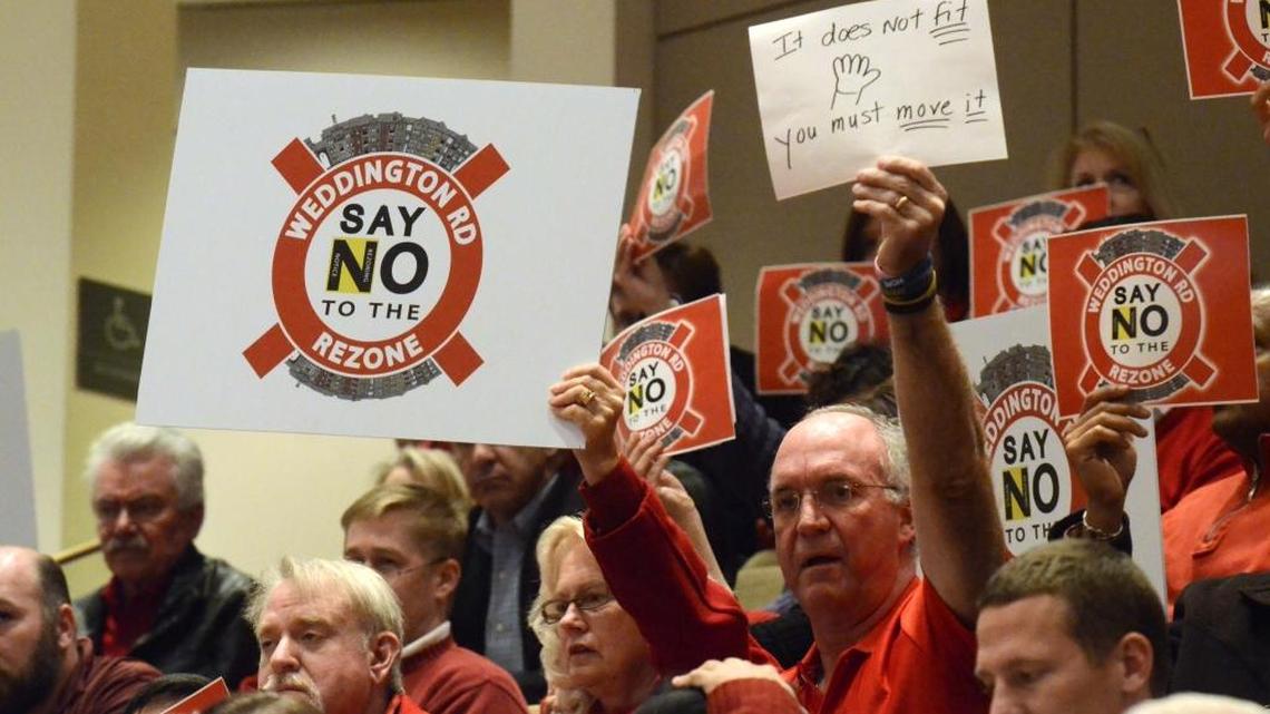 Weddington residents hold up signs in opposition to proposed low income housing in their community during Monday night's Charlotte City Council meeting Dec. 16, 2013.