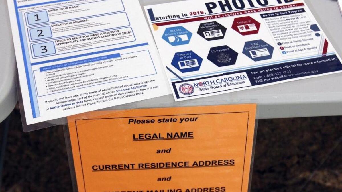 File photo: Placards on voters’ tables in Chapel Hill in 2014 alert voters to ID requirements set to go in effect in 2016. The rules are the focus of a trial that starts Monday.