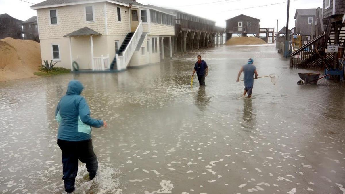 Carol Dillon, left, owner of Outer Banks Motel in Buxton on North Carolina's Hatteras Island, wades out into the flooded parking lot at her hotel as workers try to clear drain pipes during high tide on Sunday, October 4, 2015.