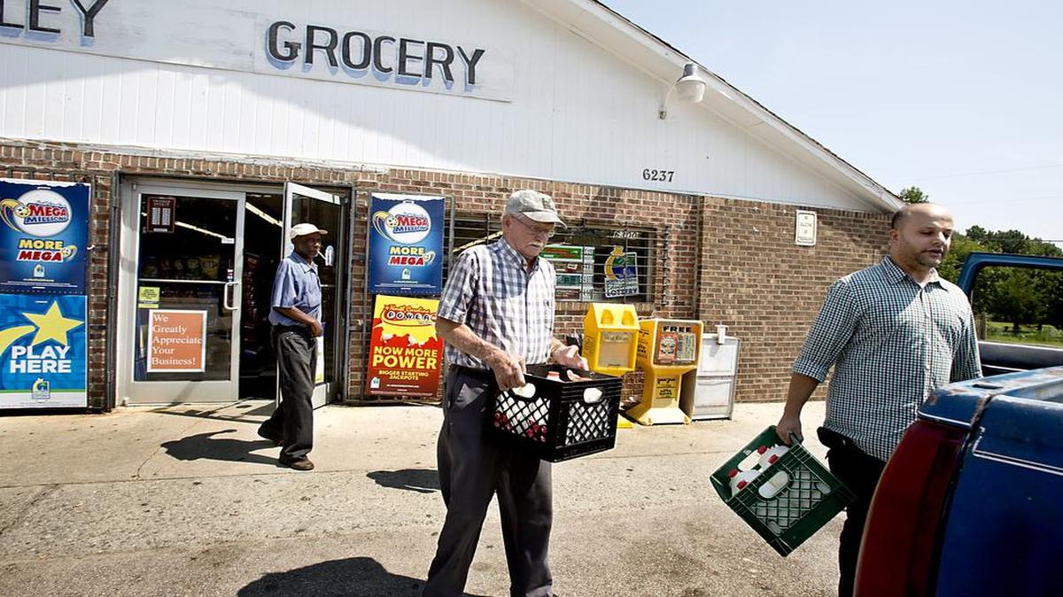 
Ray Carroll, center, and William Bradford, left, both of Raleigh, get some help loading crates of milk onto the back of their truck from Riley Mart store manager Sam Sammour near Wendell. A proposed grant program would put fresh fruits and vegetables in corner stores located in “food deserts.” 
