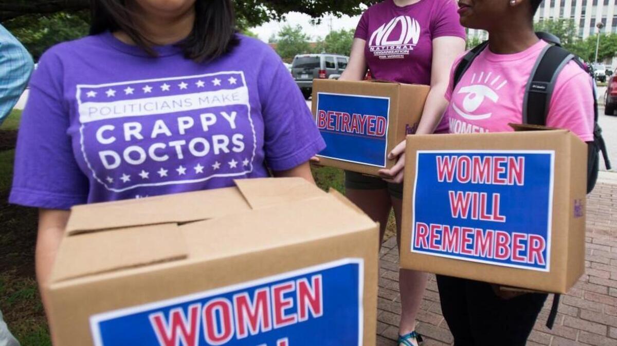 From left, Chavi Koneru, a policy director for NARAL Pro-Choice North Carolina, Maddie Majerus, a volunteer with NARAL Pro-Choice, and Emma Akpan, a field organizer with Planned Parenthood South Atlantic, rally with boxes of signed petition for Gov. Pat McCrory on Thursday, June 4, 2015 in Raleigh. McCrory signed the abortion bill opposed by the groups, and parts of the law become effective Friday.