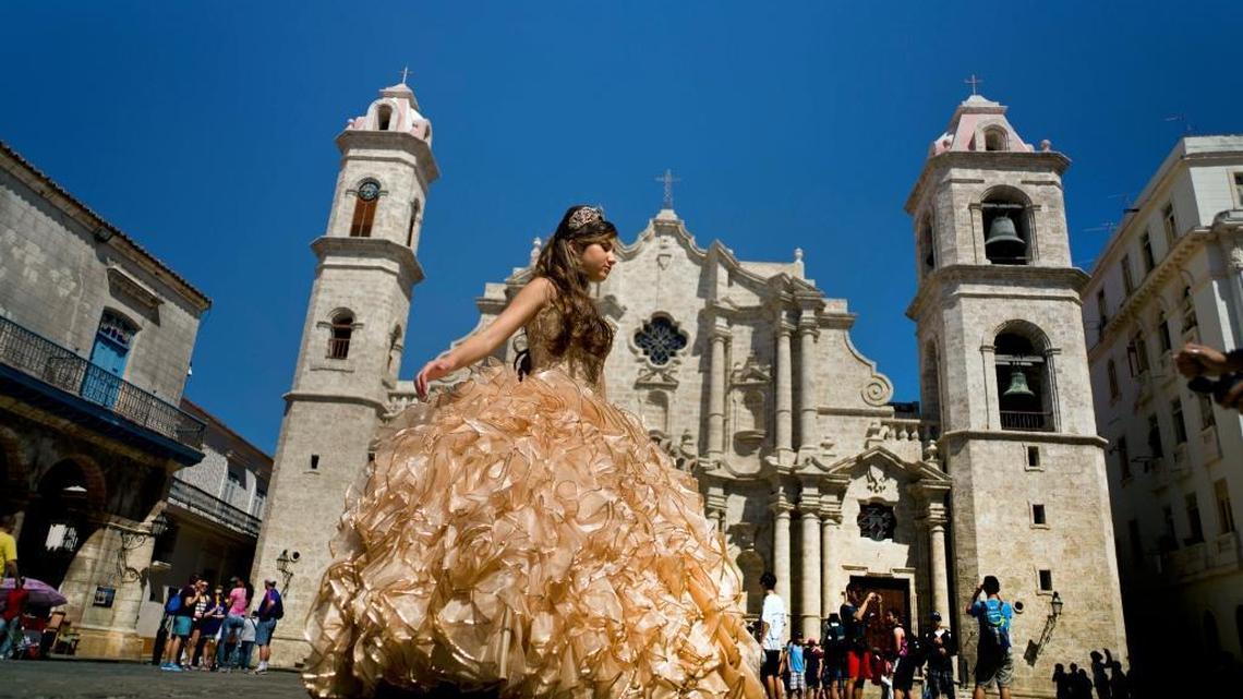 A "quinceanera" poses during her photo session in front of the cathedral as tourists line up to enter the building, in Havana, Cuba, on March 14, 2016. Lawmakers want to block scheduled commercial airline service to Cuba after more than 10 American cities won tentative government approval advancing President Barack Obama's effort to normalize relations with Cuba. (AP Photo/Ramon Espinosa, File)