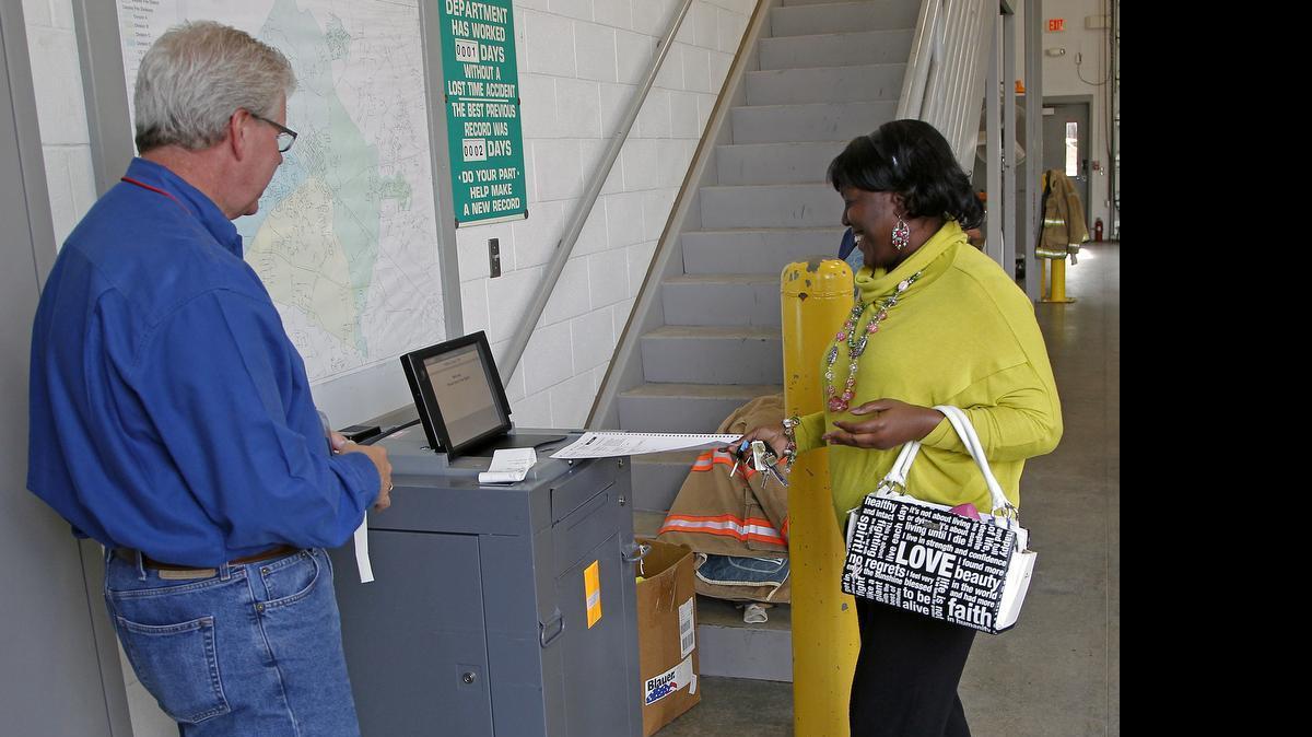 
Poll worker Robert Capps, left, watches as Cynthia Toudle, right, inserts her ballot in the voting machine at Johnston County Precinct 10a at the Clayton Fire Station in Clayton on Nov. 5, 2014. 
