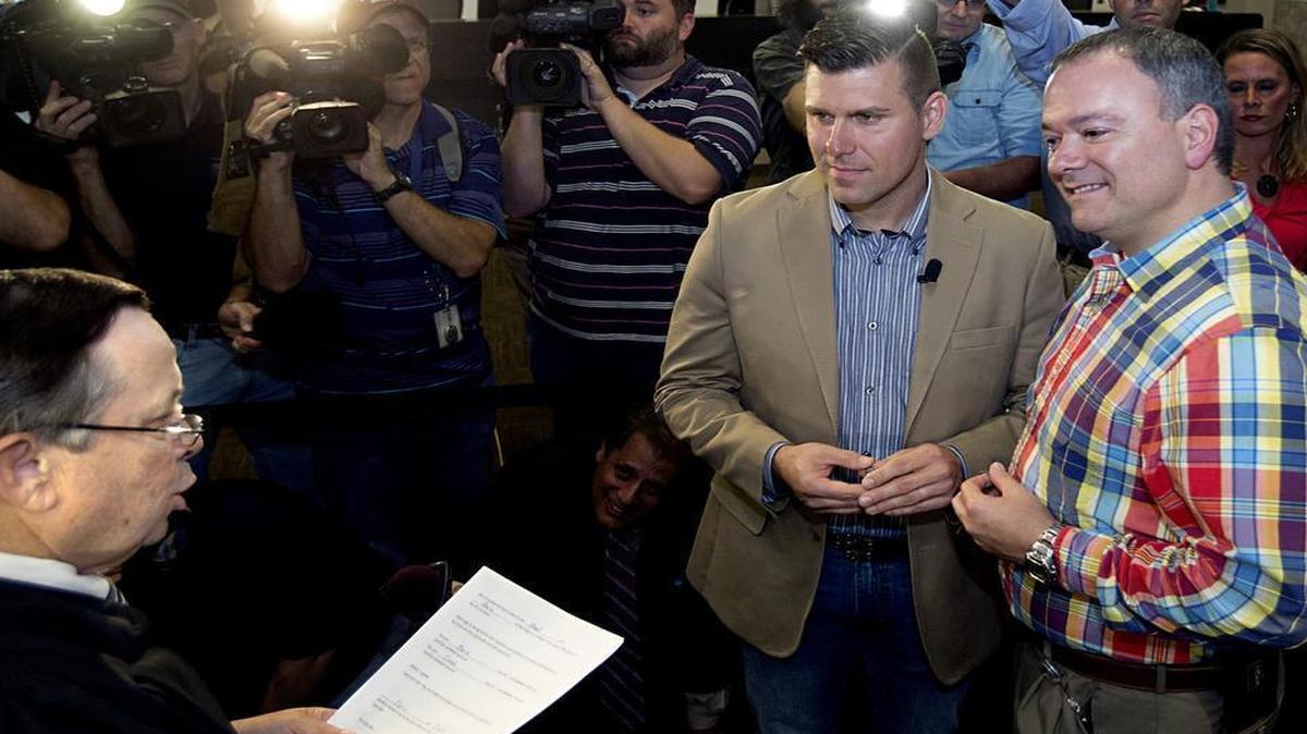 
Chad Briggs (left) and his partner Chris Creech kiss exchange wedding vows with Chief Magistrate Dexter Williams, left, presiding at the Wake County Courthouse in Raleigh, N.C. Friday, October 10, 2014. They were the first gay couple to be married in Wake County. 
