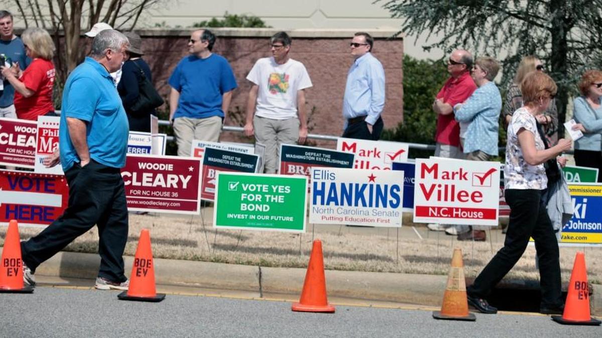 Two Wake county voters leave the early voting precinct while others wait in line to vote outside of the Herbert C. Young Community Center early voting site in Cary on March 11, 2016.