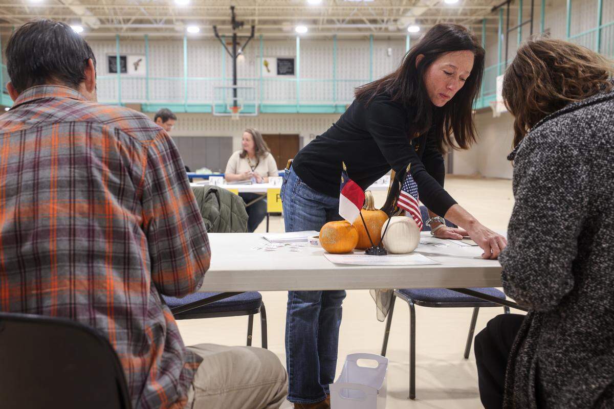 Morgan Cromwell, center, assists voters checking into precinct 36 at Providence Baptist Church early Tuesday morning in Charlotte.