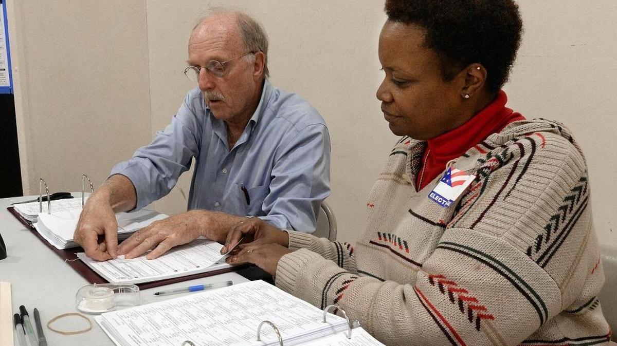 Tom Clark and Kem Gilmore work to get forms to voters at E.K. Powe Elementary School voting precinct in Durham on Nov. 8. A computer glitch shut down the county’s electronic voting system, causing some delays at some precincts.
