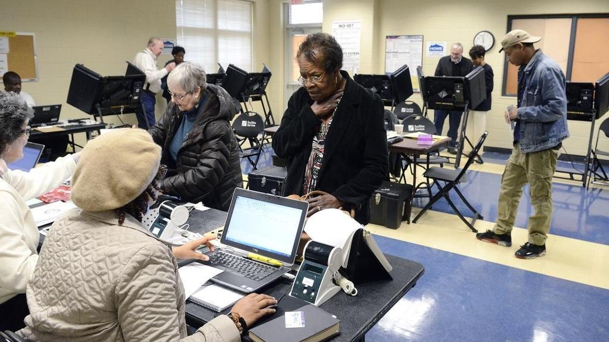 After producing her ID voter, Mary Anne Casey (center) is helped by a poll worker at CPCC's Facilities Services building in March. North Carolina voters will start voting on Oct. 20 and won’t need photo IDs this fall after a divided U.S. Supreme Court Wednesday handed another legal setback to N.C. Republicans.