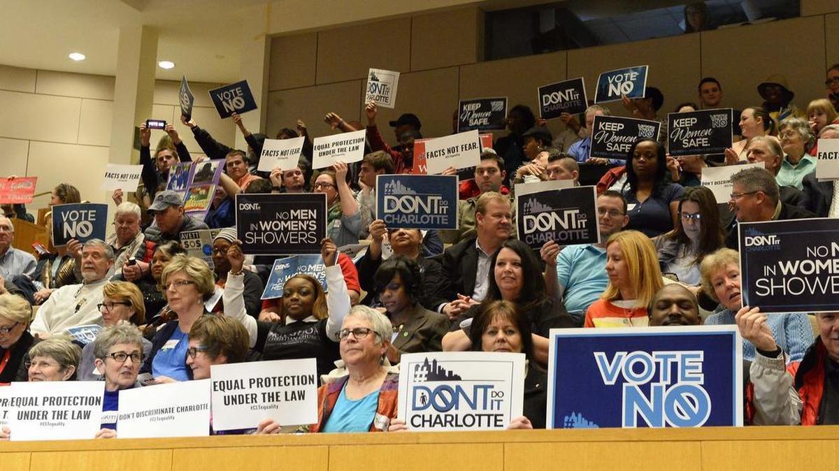 Members of the audience hold up signs before the start of the Charlotte City Council meeting to consider expanding the nondiscrimination ordinance, Feb. 22, 2016.