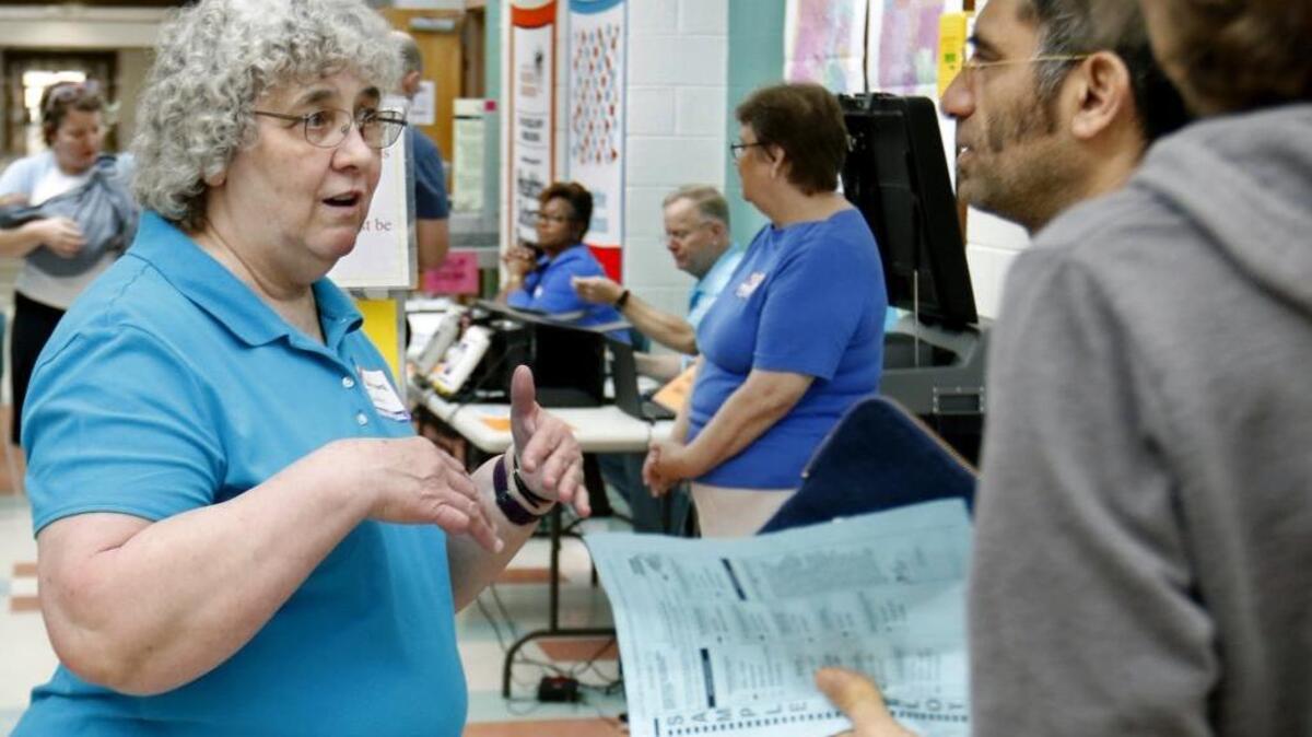 Colonial Heights precinct chief judge Barbara Turner, left, informs voters of the need for a valid ID and to turn cell phones off as they come to vote March 15 in the front hallway of Smith Middle School in Chapel Hill.