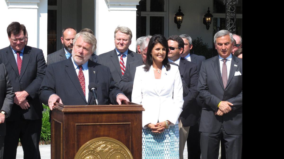 
South Carolina Commerce Secretary Bobby Hitt, at podium, talks about Volvo Car Corp.'s announcement it will build its first plant in North America in Berkeley County as Gov. Nikki Haley, second right, listens on Monday, May 11 2015, in Columbia, S.C. South Carolina beat out four other states for the $500 million plant that will employ 4,500 workers. 
