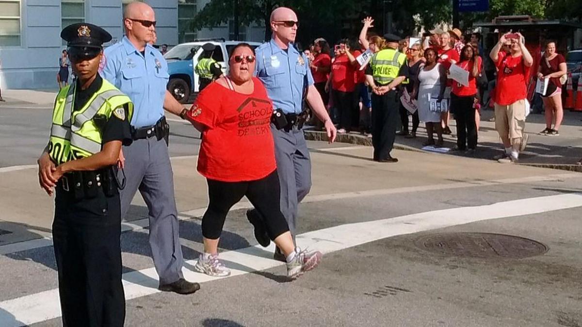 A protester is led away by police at a demonstration by teachers and supporters held near the State Capitol in Raleigh, NC on June 15, 2016. At least 14 people, including several teachers, were arrested Wednesday evening after they blocked a busy downtown intersection during a protest of Gov. Pat McCrory’s education policies.