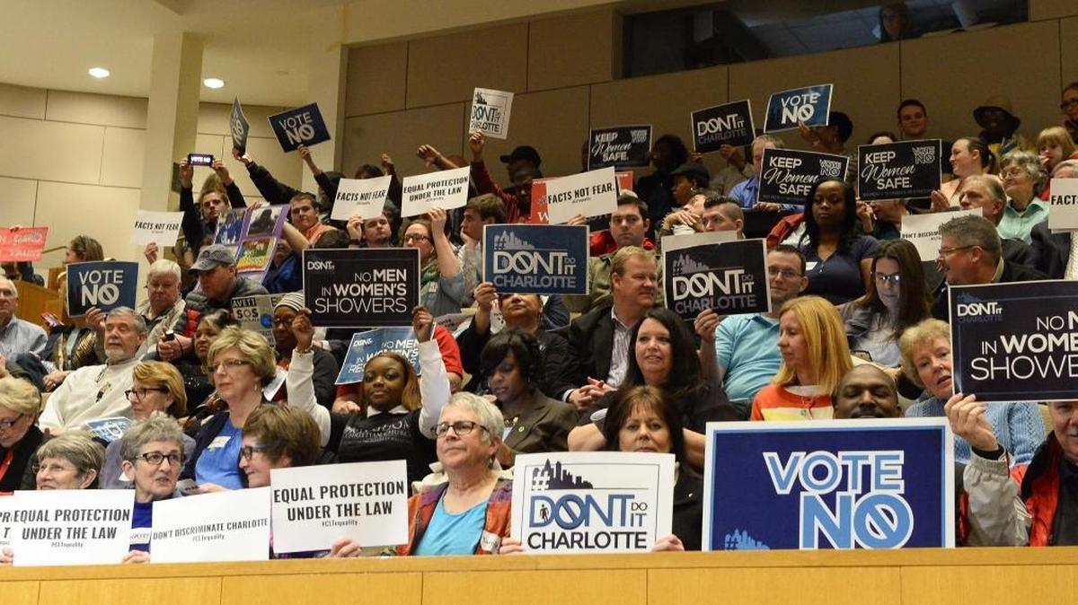 Members of the audience hold up signs before the start the City Council meeting’s vote on the nondiscrimination ordinance, Feb. 22, 2016.