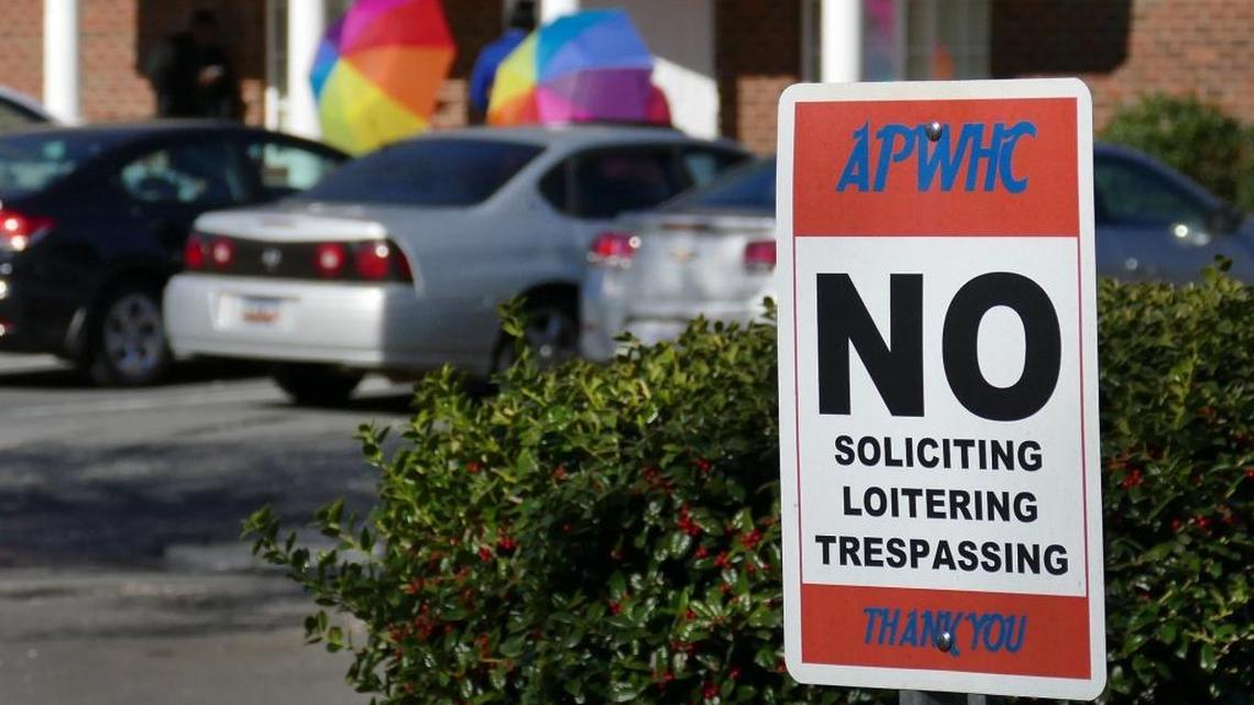 Customers are shielded with umbrellas as they enter the A Preferred Women's Health Center of Charlotte. The clinic said its phones and Internet was severed Tuesday in what the clinic said was a cyber-attack.