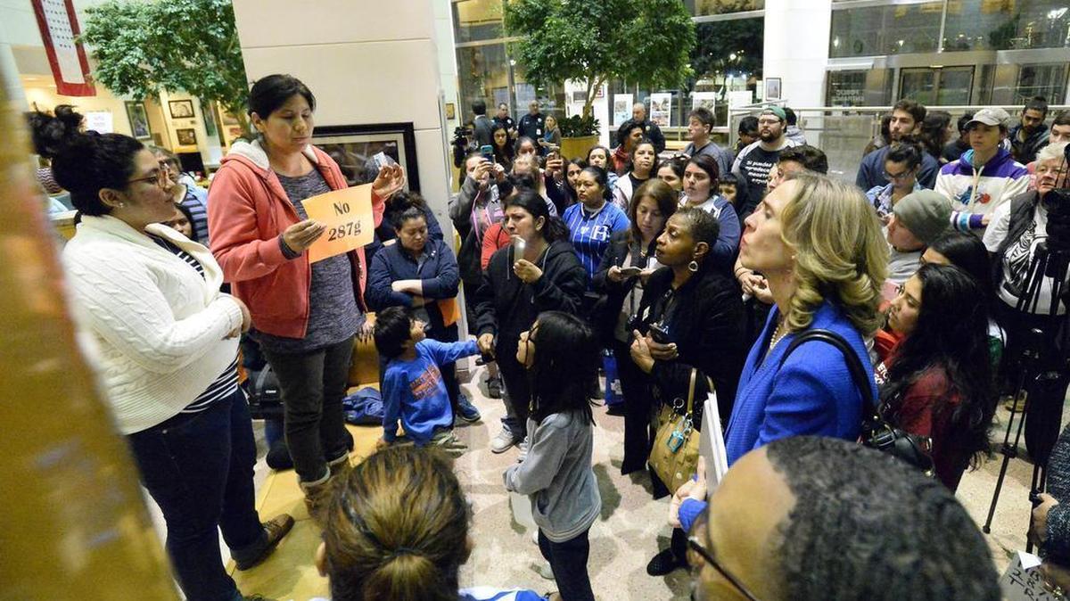 An audience member stands on a bench outside the meeting chamber at the Charlotte-Mecklenburg Government Center and addresses her concerns about ICE raids as Mayor Jennifer Roberts, right, and Council Member James Mitchell, Jr. , front right, listen after the Charlotte City Council meeting on Monday, February 27, 2017. In 2006, Roberts voted to support the Sheriff’s Office partnership with the federal government under the 287(g) program.