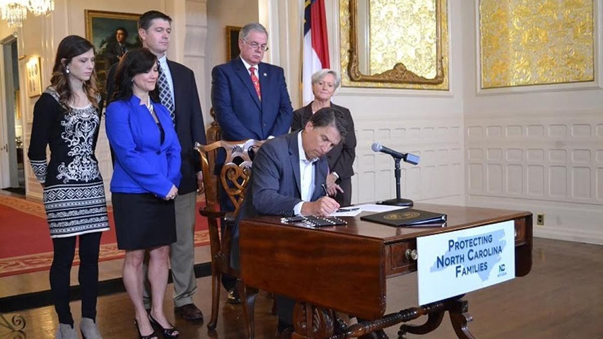 
Gov. Pat McCrory signs the “Baby Carlie Nugent Bill” to screen for severe combined immunodeficiency as bill co-sponsors Rep. Gale Adcock, right, and Rep. Donny Lambeth, second from right, look on with members of the Nugent family.
