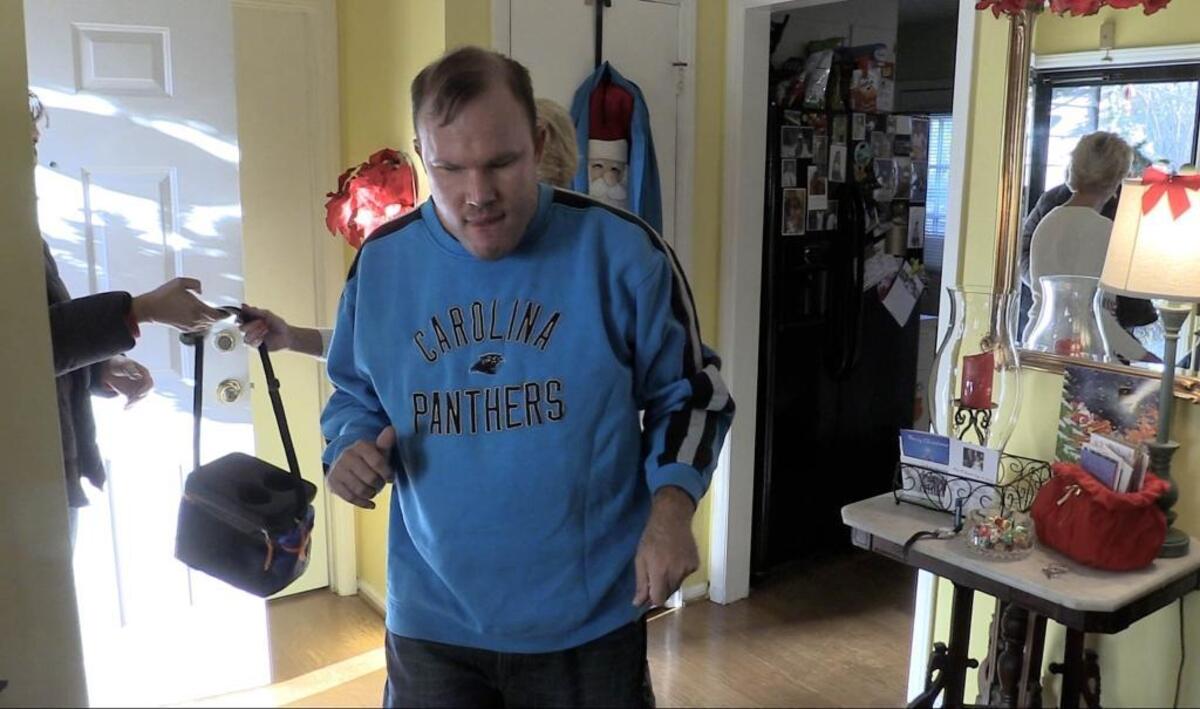 Troy Adams, 29, walks to his favorite chair after coming home from an adult day program on Monday, December 11, 2017. Troy who has developmental disabilities, and his parents have been waiting on a waiver from Cardinal Innovations for over seven and a half years.