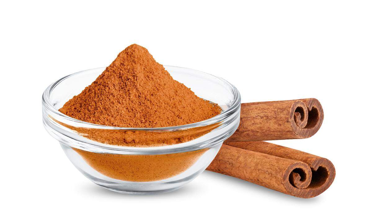 A close-up of a plastic-wrapped package of “Cinnamon Powder” from the “Lucky Foods” brand. The orange label features a small mound of the powder and text in English, Russian (Карица молотая), and Georgian, with a weight of 40g and the label “Georgian Dry Spices.”