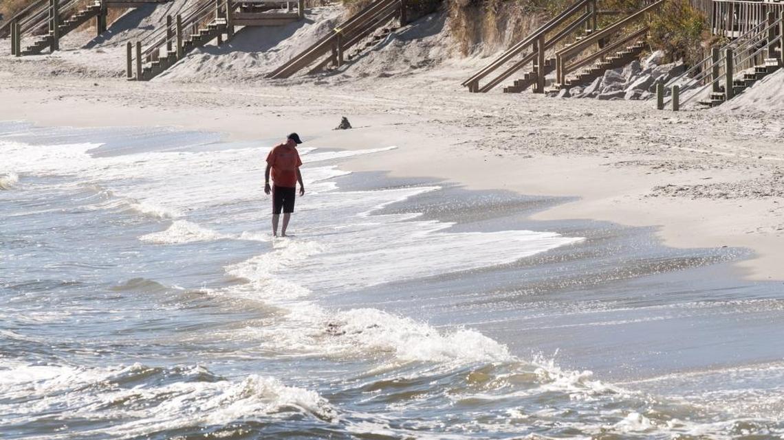 A beach comber walks along a narrow strip of high tide beach at Cherry Grove last month, one of several area beaches affected by October’s unusually turbulent weather.