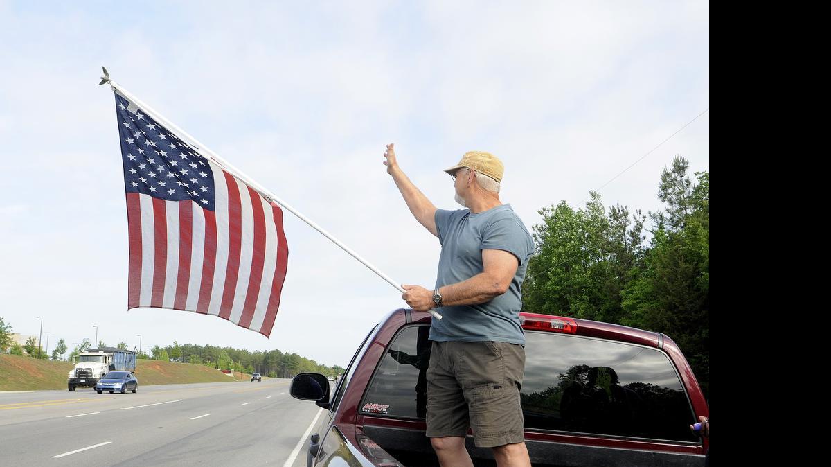 
Keith Lyon waves to drivers along the S.C. 5 Bypass Thursday morning during a flag protest outside York Comprehensive High School. Dozens of students and adults lined up along the road in protest of a York student who was told to remove an American flag from his vehicle. 
