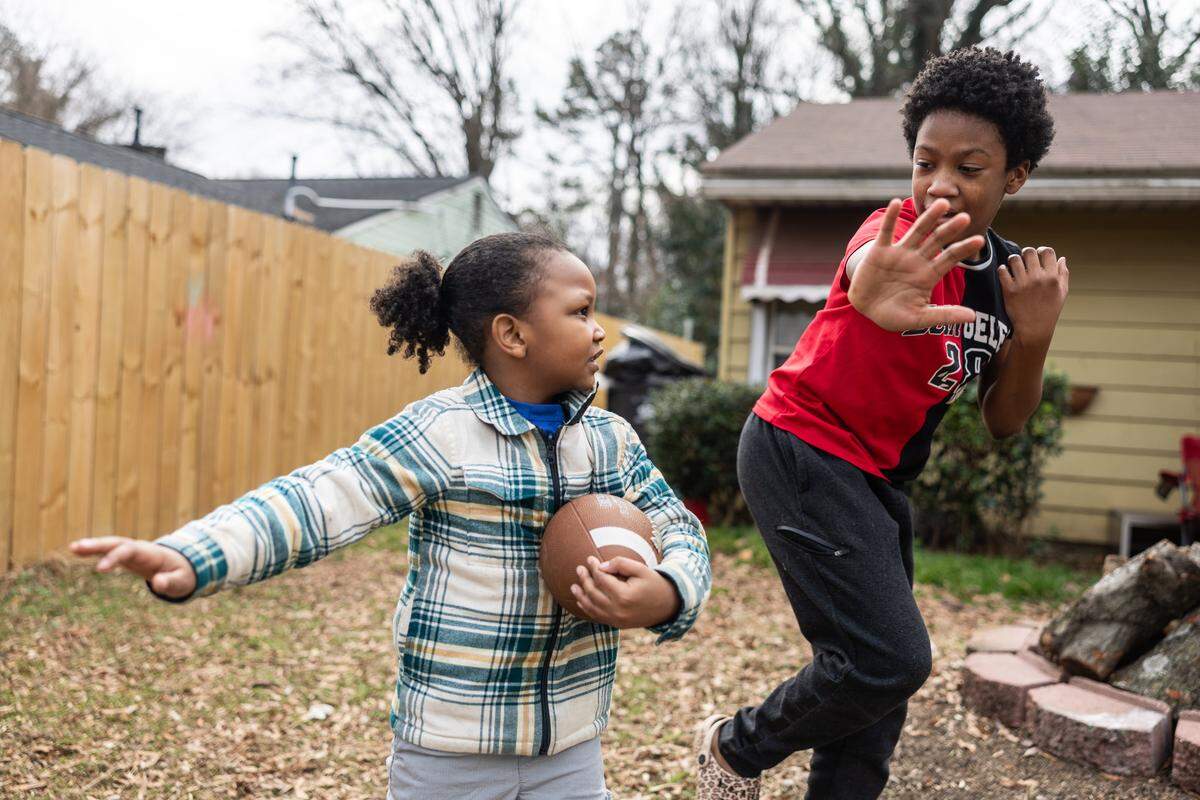 Zemarion Fuentes, 13, right, teaches his brother, Camp Wallace, 5, how to make the Heisman pose with a football in their front yard in Charlotte. The city broke a 70-year-old Christmas Day temperature record by reaching 79 degrees.