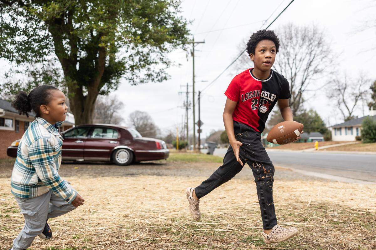 Zemarion Fuentes, 13, right, and his brother, Camp Wallace, 5, play football in their front yard in Charlotte, on Friday, Dec. 26. The region broke a temperature record on Christmas Day, reaching nearly 80 degrees.