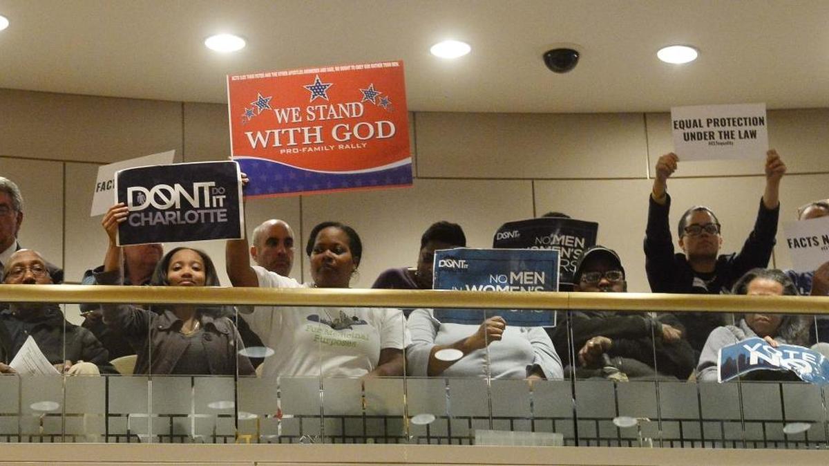 Members of the audience hold up signs at Monday's City Council meeting.