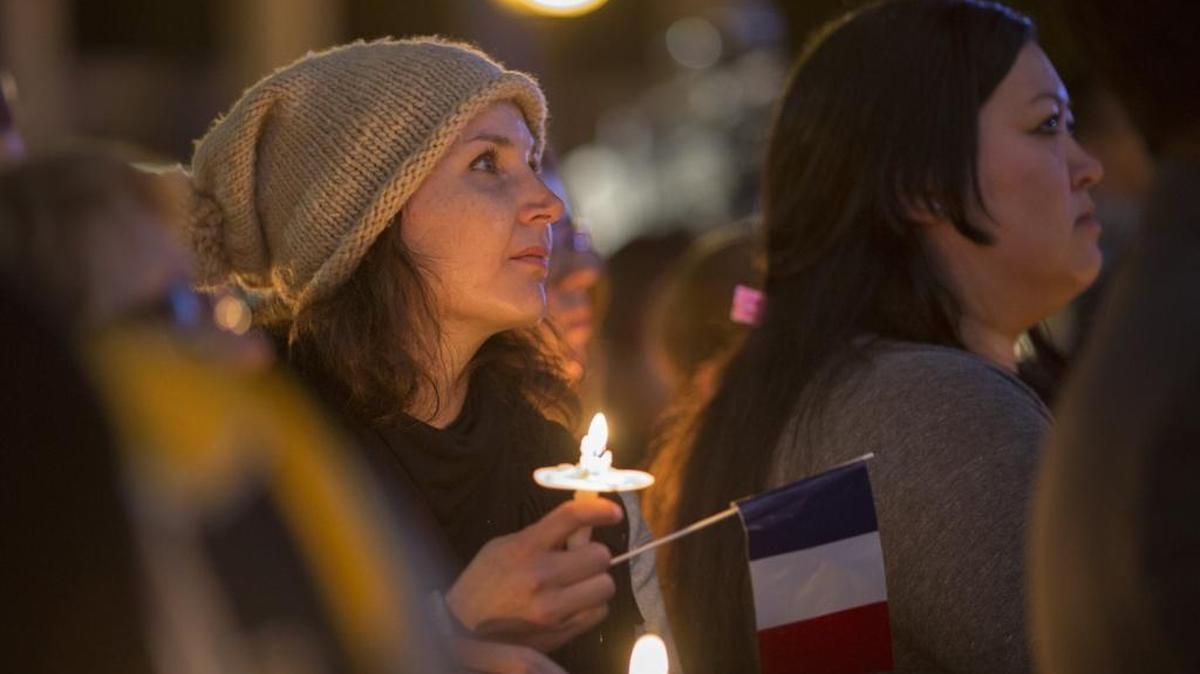 A woman holds a French flag at a memorial and vigil outside Los Angeles City Hall for the victims of the Paris attacks.