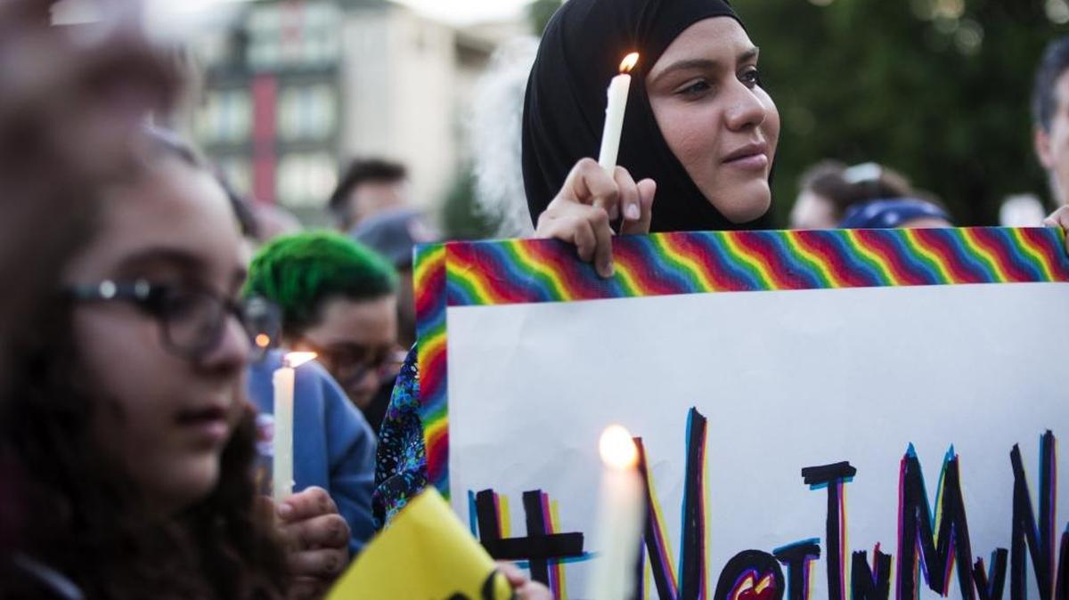 Zuleyha Ozonder, who is Muslim, holds a candle and a sign that references the hashtag "#NotInMyName" to show that many in the Islamic faith support the LGBTQ community during a vigil at Cal Anderson Park in Seattle on Sunday.