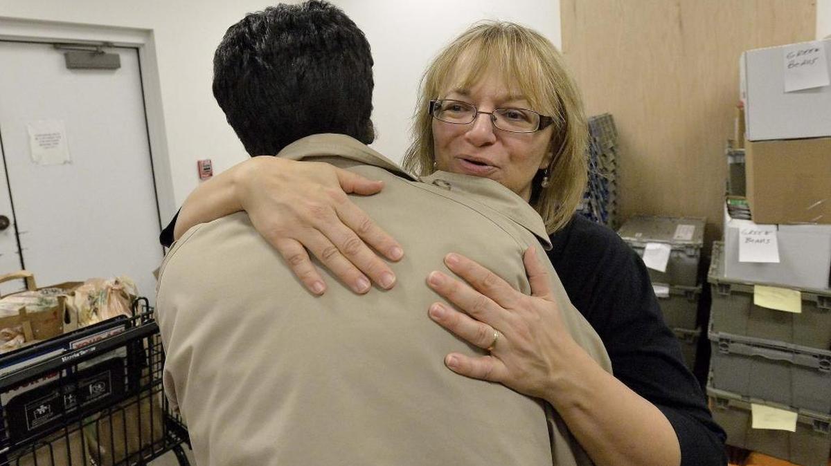 Lucy Mitchell (left), with Loaves & Fishes, hugs client Geneva Robinson last Christmas Eve after helping her pick out groceries at a food pantry.