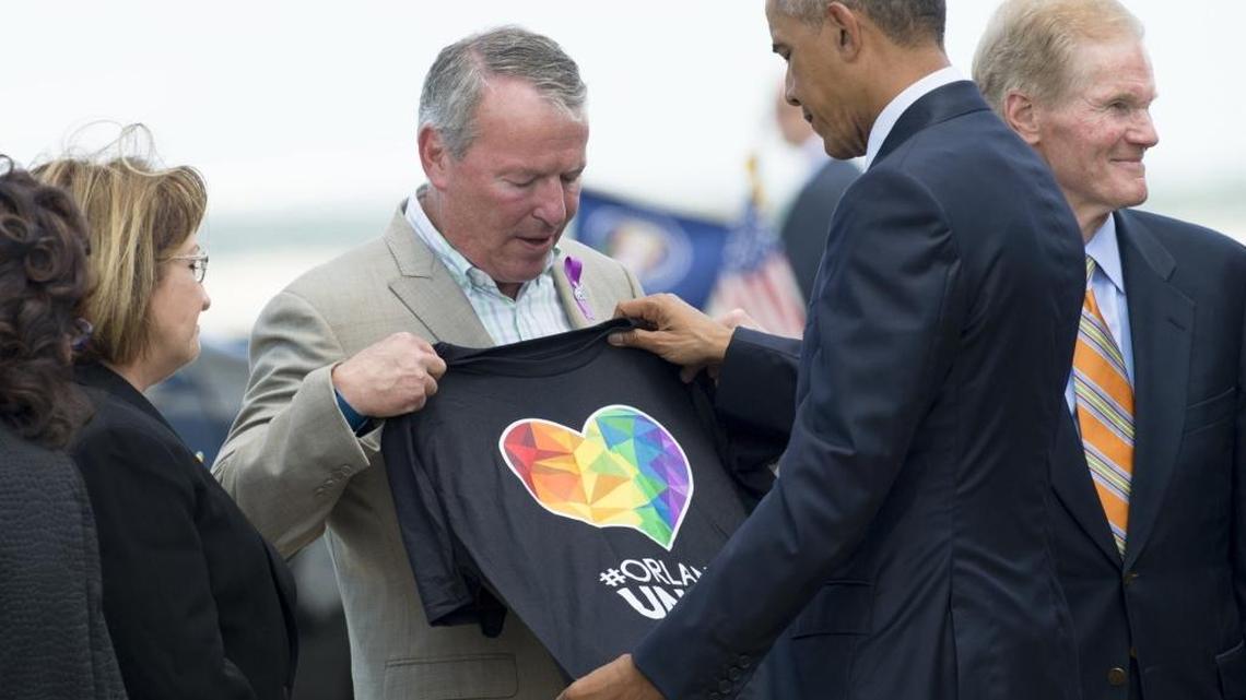 Orlando Mayor Buddy Dyer holds an “Orlando United” T-shirt Thursday while greeting President Barack Obama.