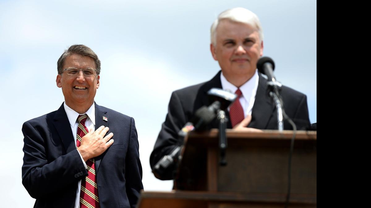 
North Carolina Governor Pat McCrory, left, listens to the National Anthem with NCDOT Chairman Ned Curran, right, during the opening of the final section of the outer belt in Charlotte in June.
