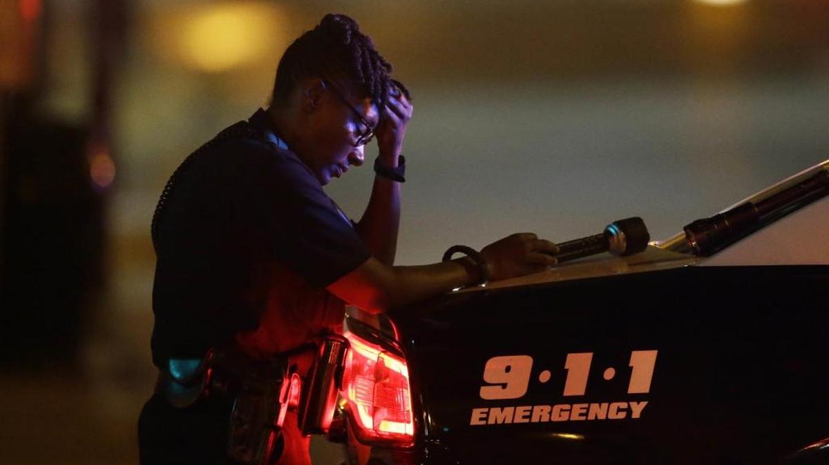 A Dallas police officer, who did not want to be identified, takes a moment as she guards an intersection early Friday.