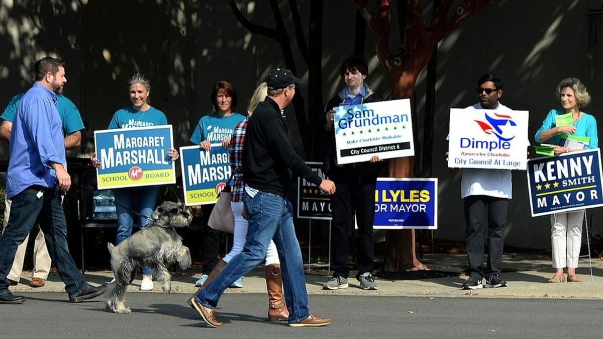 Voters walk past a line of campaigners on the last day of 2017 early voting.