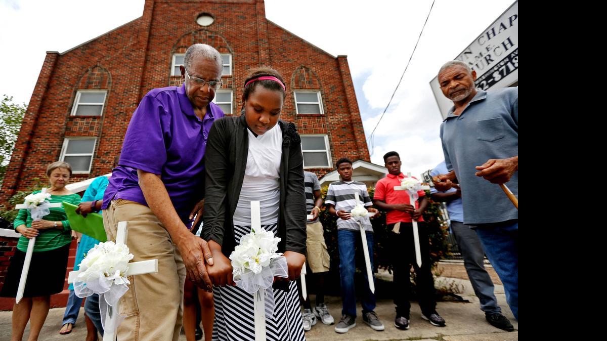 
Kennedy Honors, 12, gets help placing one of nine crosses in memory of the Charleston victims at a Houston church.
