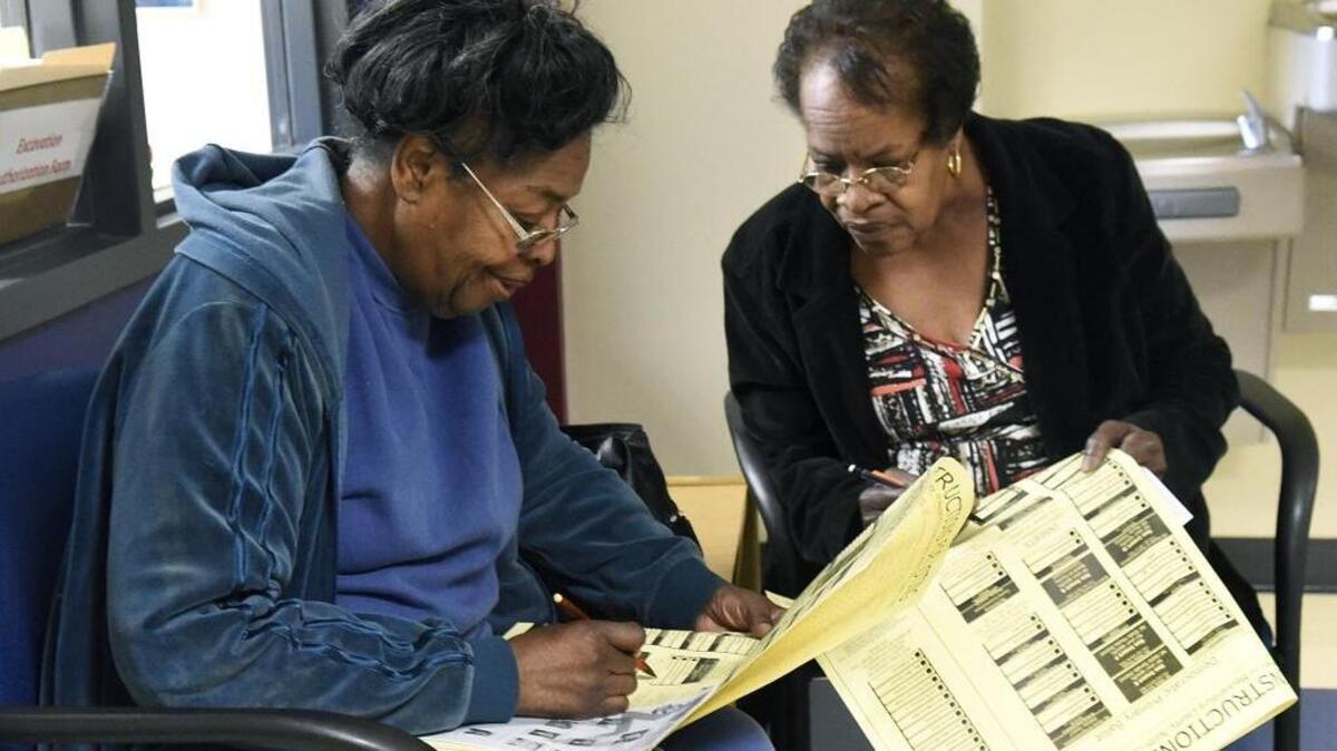 Sisters Marie McCombs (left) and Mary Anne Casey read over the ballot before casting their votes last year. North Carolina’s voter ID law died Monday, but could be resurrected.