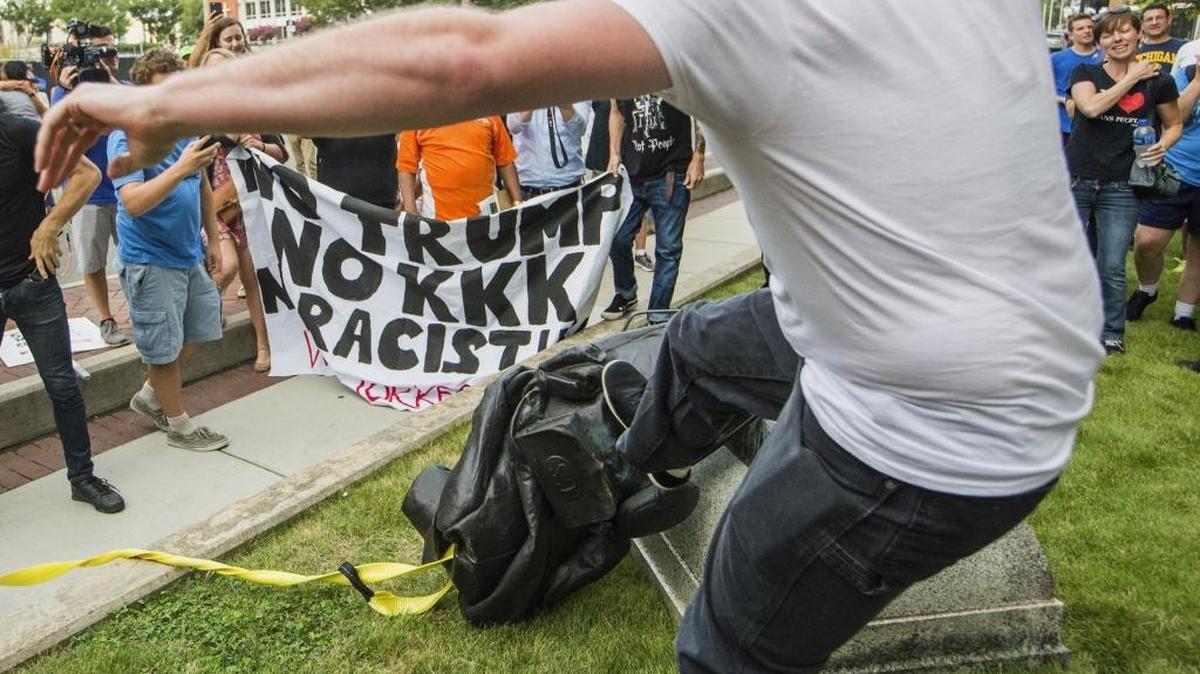 A protester kicks the toppled statue of a Confederate soldier after it was pulled down in Durham on Monday.