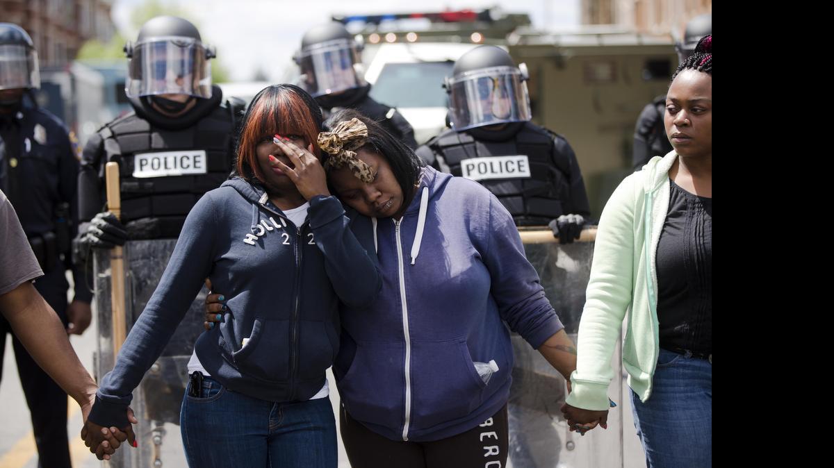 
Sisters Jerrie Mckenny (left) and Tia Sexton embrace as people sing Amazing Grace Tuesday in Baltimore.
