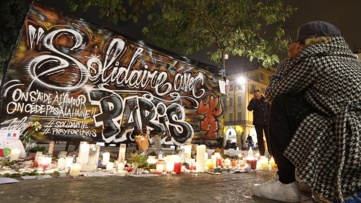 A woman sits before a makeshift memorial on Monday in Nice, in tribute to the attacks in Paris.