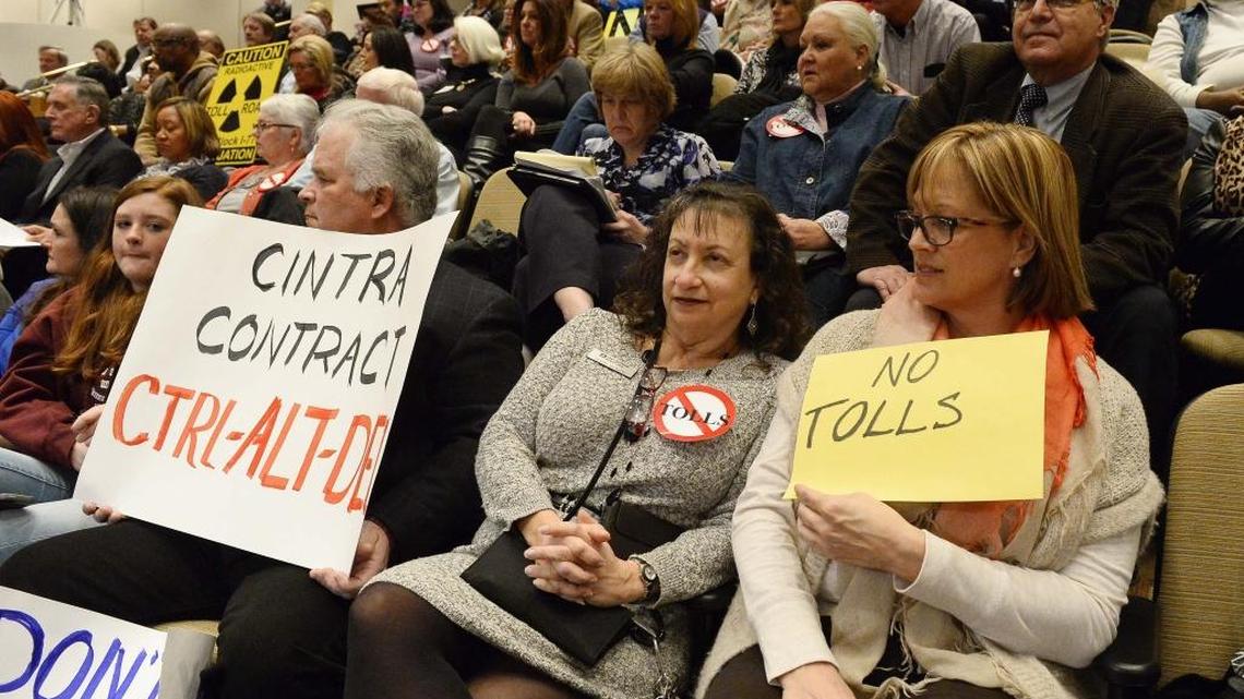 Residents protesting toll lanes on Interstate 77 hold up signs during Monday's Charlotte City Council meeting.