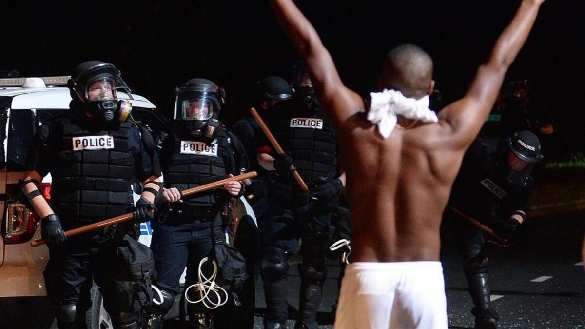 A protestor approaches CMPD officers with his arms up on Old Concord Road during a protest Tuesday night.