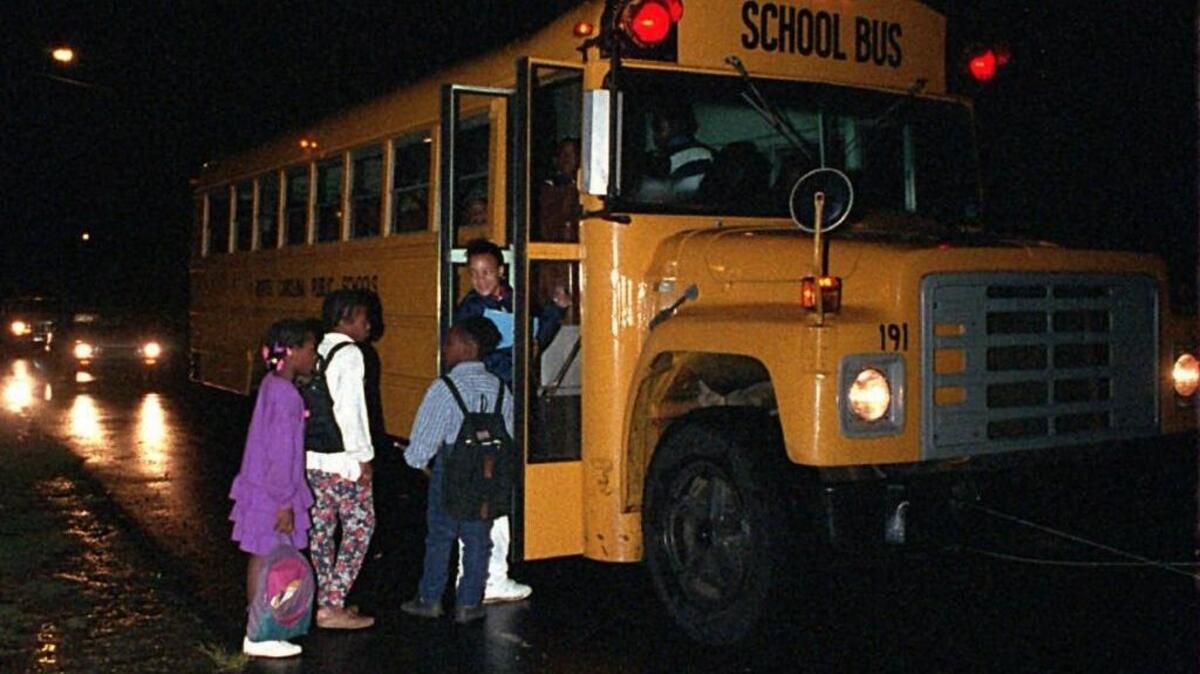 In 1995, Sharon Elementary students board their bus while it’s still dark off Steele Creek Road. Their parents were concerned about busing and wanted a neighborhood school.